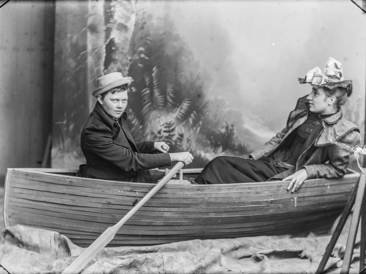 The photography shows two women sitting in a rowing boat. The scene takes place in a photo studio in front of a painted background. GUIDED TOUR & DRINKS as part of the exhibition: LIKE A WHIRLWIND